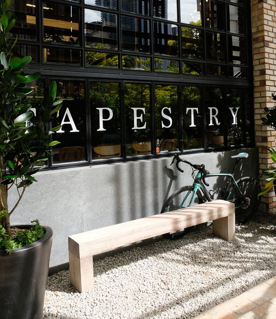 Tapestry Chow Kit: a timber bench and a bicycle against the concrete and brick shopfront on Jalan Kamunting