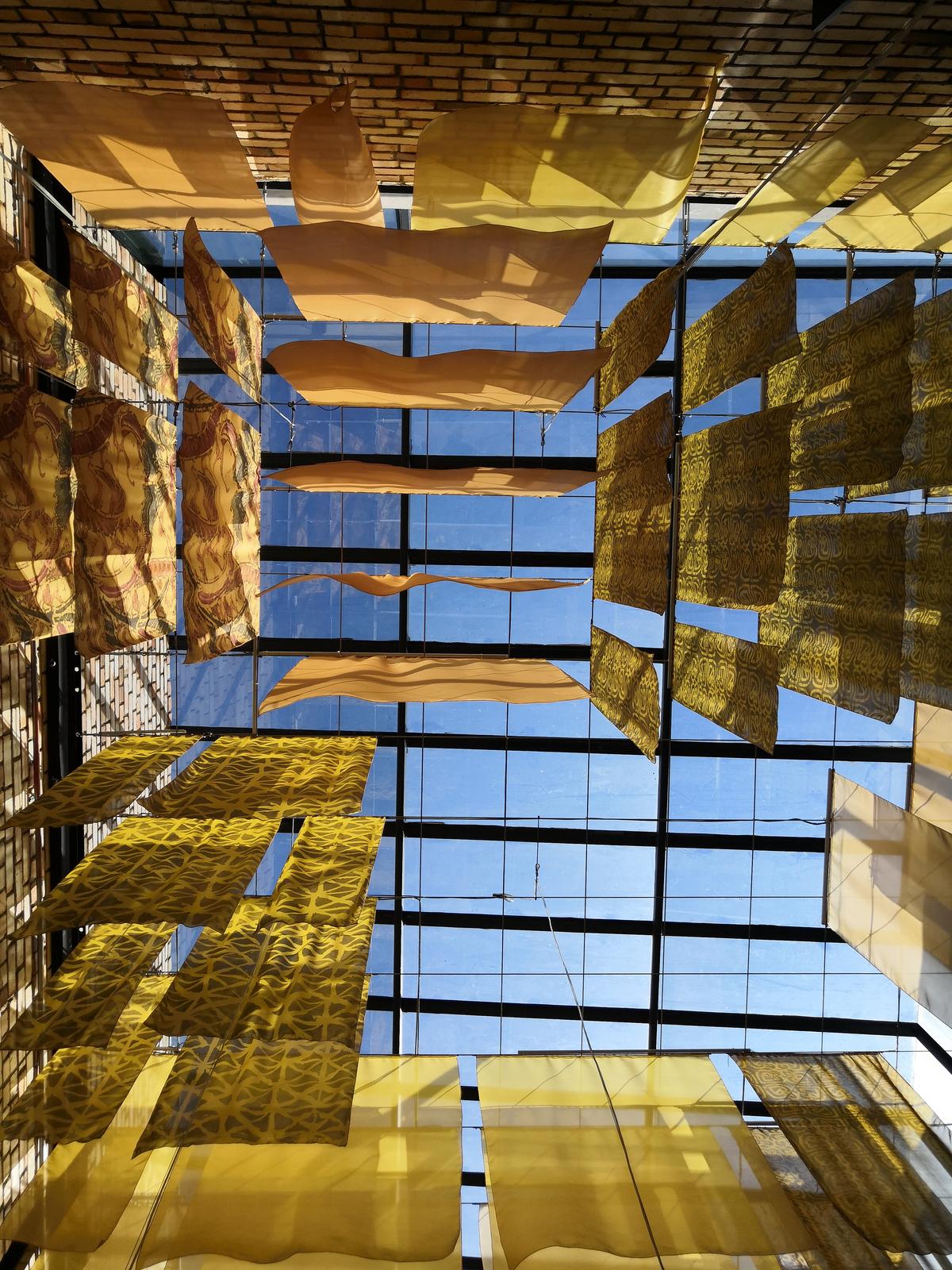 Batik and songket panels suspended on wires in Tapestry's full-height skylight